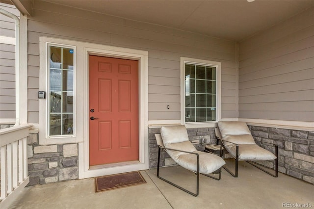 view of exterior entry featuring covered porch and stone siding