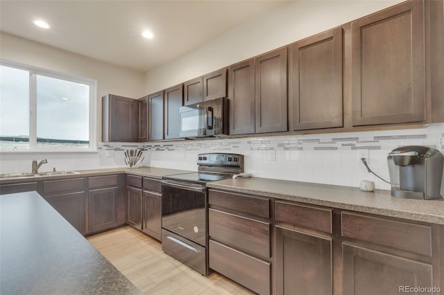 kitchen featuring light wood-type flooring, recessed lighting, a sink, backsplash, and stainless steel electric range oven