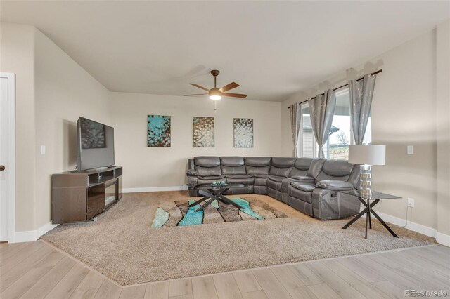 living area with a ceiling fan, baseboards, and wood finished floors