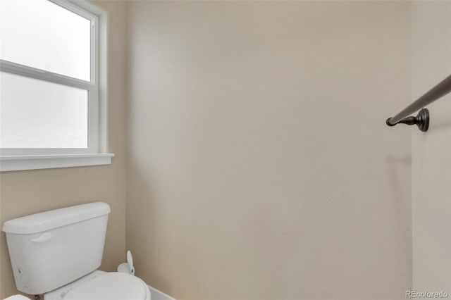 bathroom featuring toilet, baseboards, and a healthy amount of sunlight
