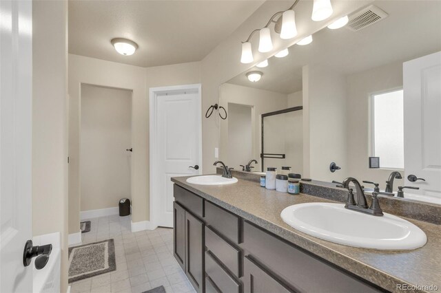 bathroom featuring a sink, a shower stall, double vanity, and visible vents