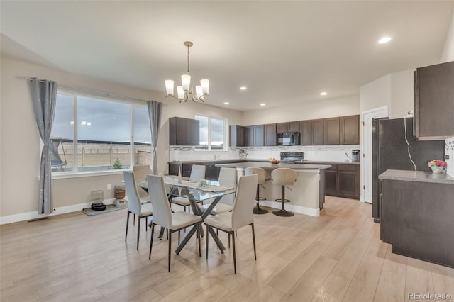 dining space featuring recessed lighting, baseboards, a notable chandelier, and light wood-style flooring