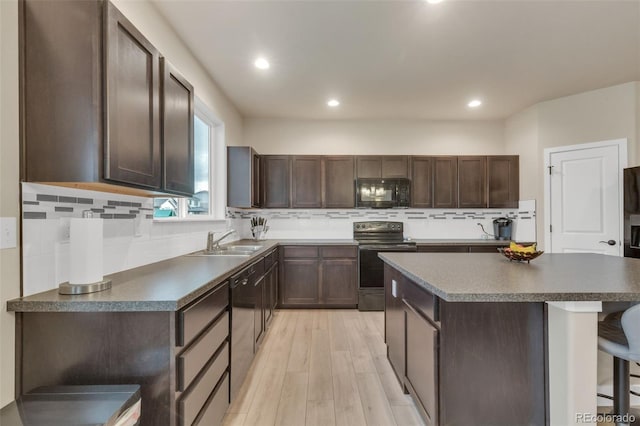 kitchen featuring black microwave, a sink, light wood-style floors, electric stove, and dishwashing machine