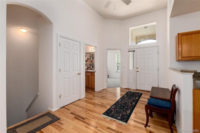 entrance foyer featuring ceiling fan, light hardwood / wood-style flooring, and a towering ceiling