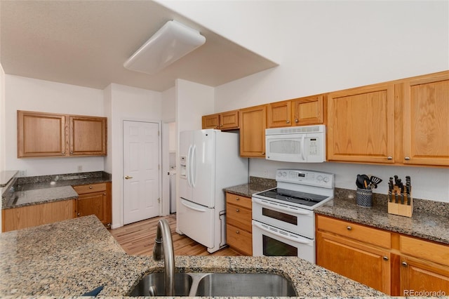 kitchen featuring white appliances, light wood-type flooring, dark stone countertops, and sink