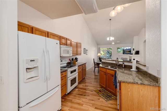 kitchen with white appliances, hanging light fixtures, light hardwood / wood-style floors, an inviting chandelier, and sink