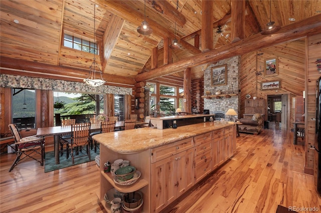 kitchen with light hardwood / wood-style flooring, decorative light fixtures, light stone countertops, beam ceiling, and a center island