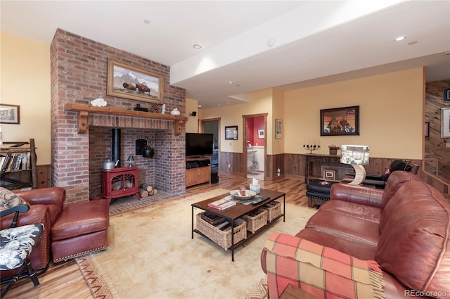 living room featuring a wood stove, brick wall, and light wood-type flooring