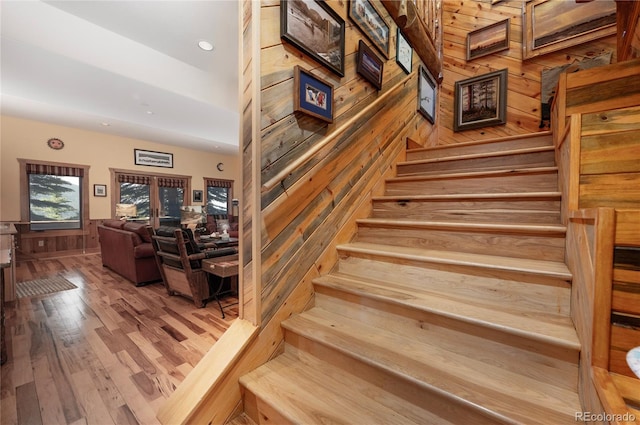 stairs featuring hardwood / wood-style flooring and wooden walls