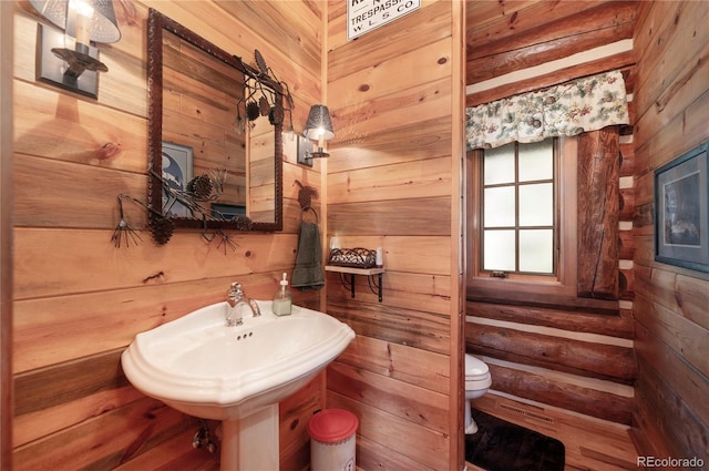 bathroom featuring wooden walls and toilet