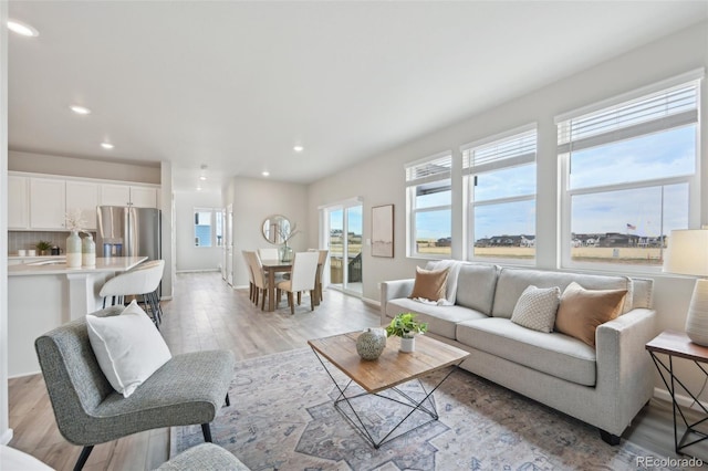 living room with recessed lighting, light wood-style flooring, and baseboards