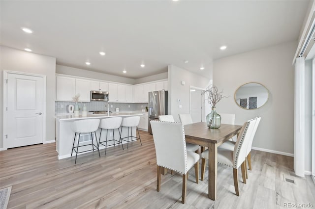 dining space featuring light wood-style floors, baseboards, visible vents, and recessed lighting