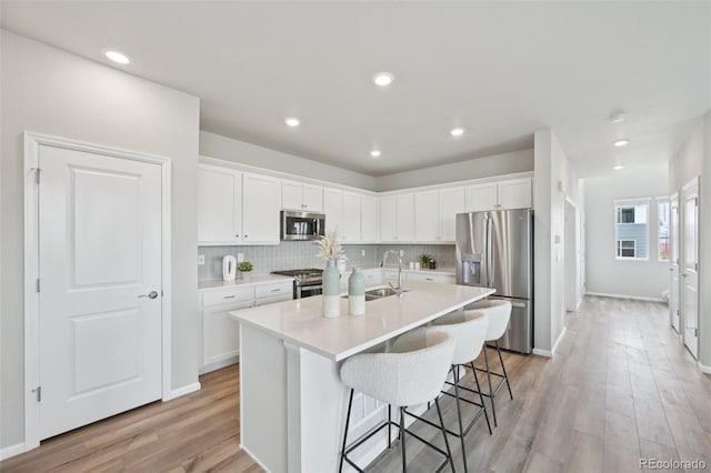 kitchen with decorative backsplash, a kitchen breakfast bar, white cabinetry, and stainless steel appliances