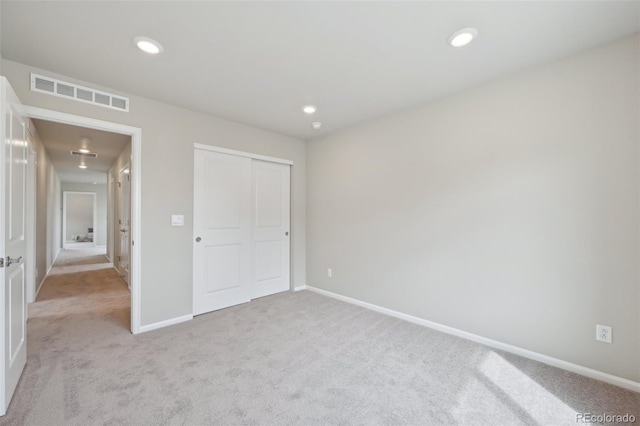 unfurnished bedroom featuring baseboards, a closet, light carpet, recessed lighting, and visible vents