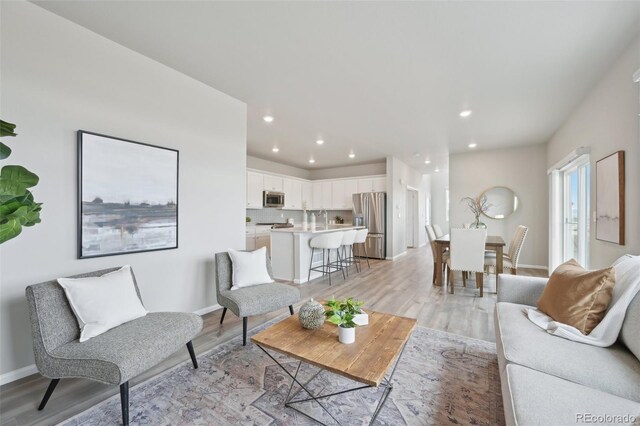 living area with light wood-type flooring, baseboards, and recessed lighting