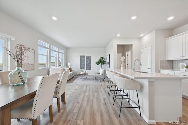 kitchen featuring a sink, white cabinets, a kitchen island with sink, and light wood-style floors