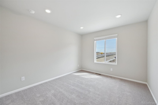 carpeted empty room with baseboards, visible vents, and recessed lighting