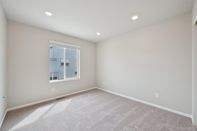 carpeted empty room with visible vents, baseboards, and recessed lighting