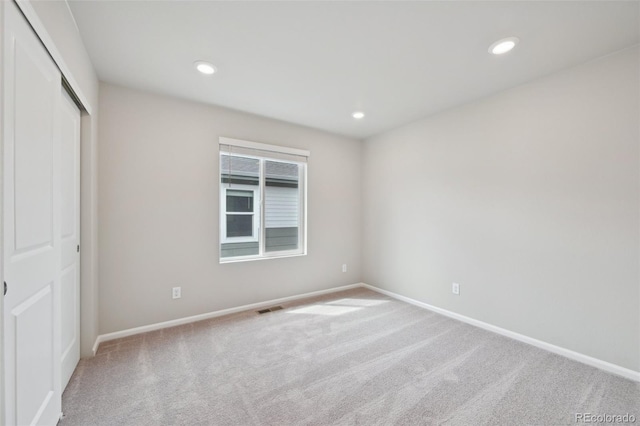 unfurnished bedroom featuring a closet, baseboards, recessed lighting, carpet floors, and visible vents