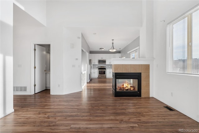 unfurnished living room featuring dark hardwood / wood-style flooring and a tiled fireplace