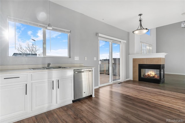 kitchen with stainless steel dishwasher, dark hardwood / wood-style floors, a multi sided fireplace, and white cabinets