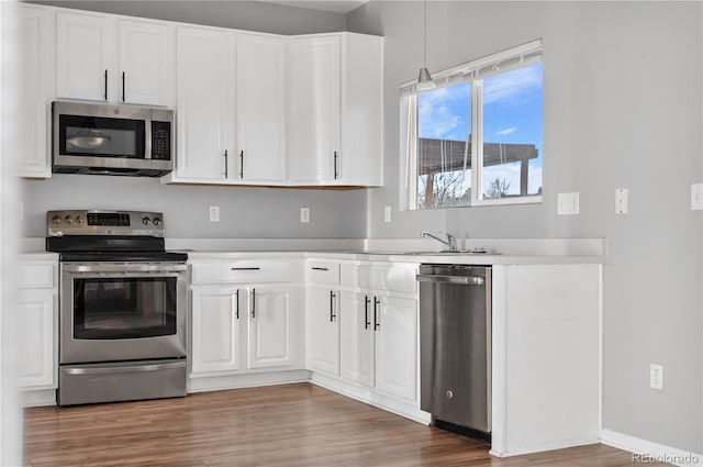 kitchen featuring hardwood / wood-style flooring, sink, white cabinetry, and stainless steel appliances