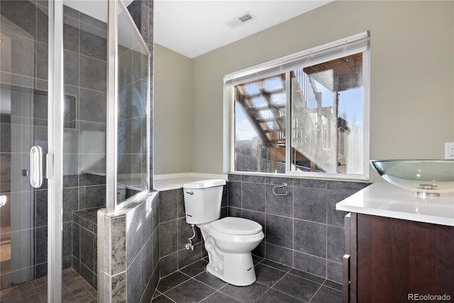 5241 S Shawnee St, Aurora, CO 80015 - bathroom with tile walls, vanity, a stall shower, tile patterned floors, and wainscoting
