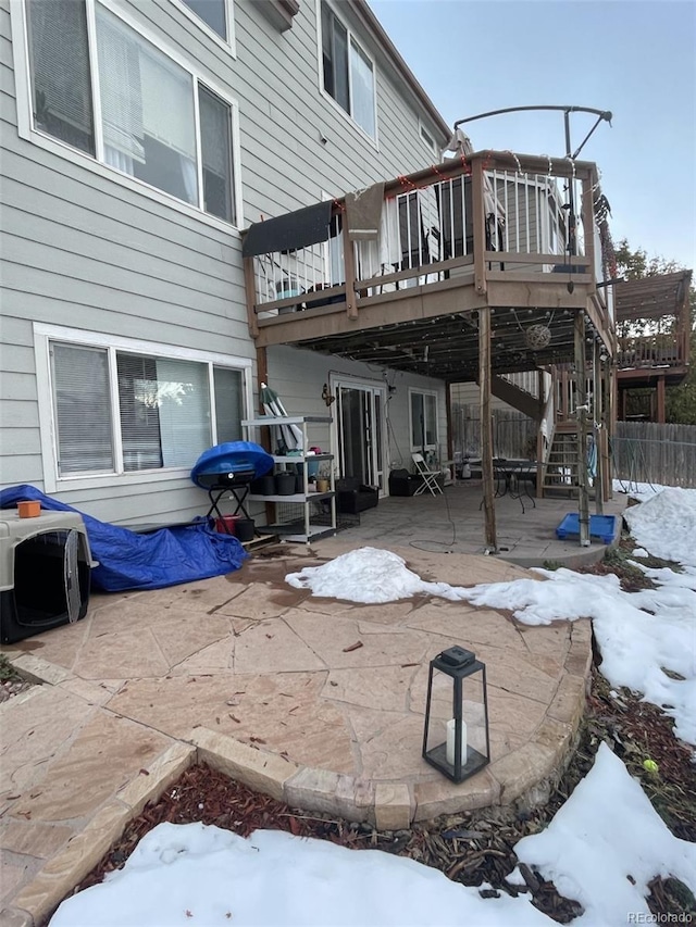 snow covered patio featuring a wooden deck