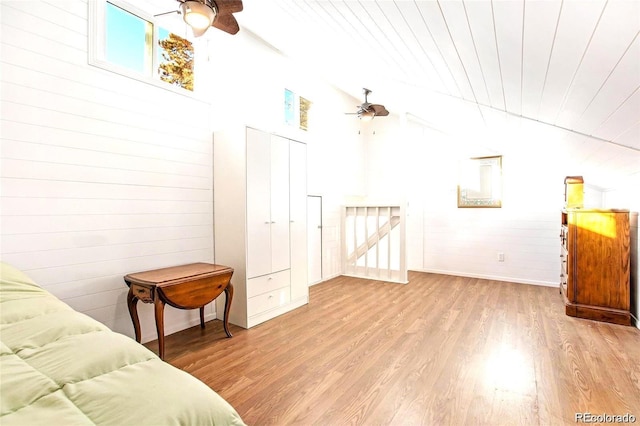 bedroom with wooden walls, wood finished floors, lofted ceiling, ceiling fan, and wooden ceiling