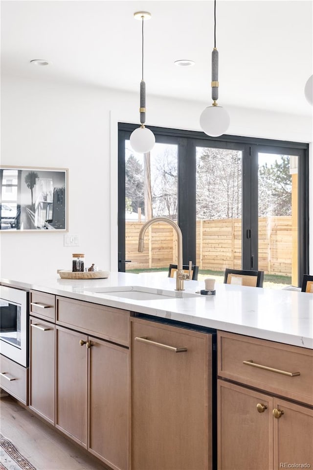 kitchen featuring sink, hanging light fixtures, light wood-type flooring, and stainless steel appliances