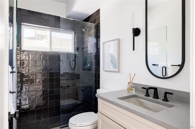 bathroom with a shower with shower door, vanity, and toilet