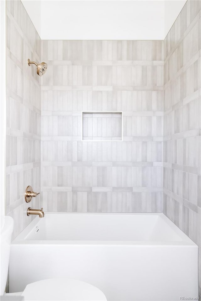 bathroom with toilet and tiled shower / bath combo