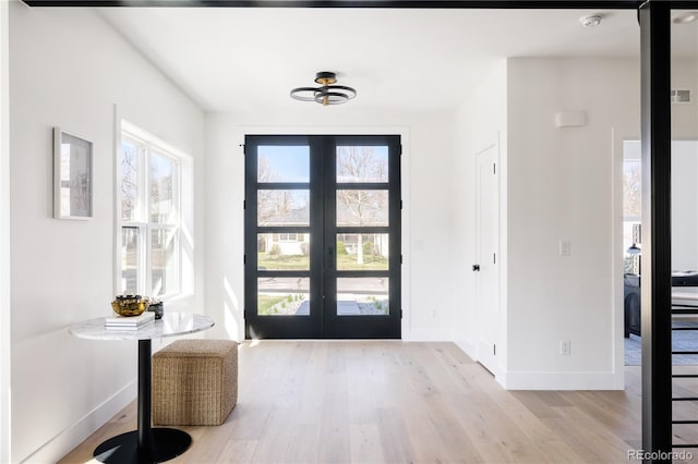 foyer with french doors, light wood finished floors, and baseboards