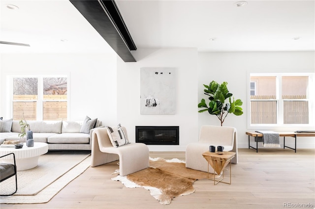 living area featuring light wood-style floors, a glass covered fireplace, baseboards, and recessed lighting