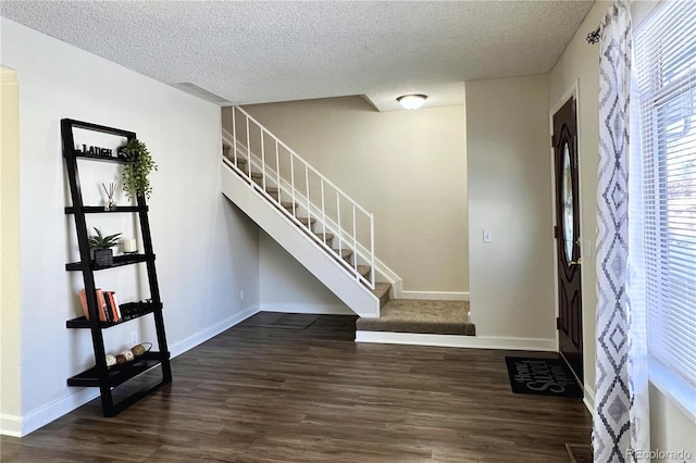 entryway with dark wood-type flooring and a textured ceiling