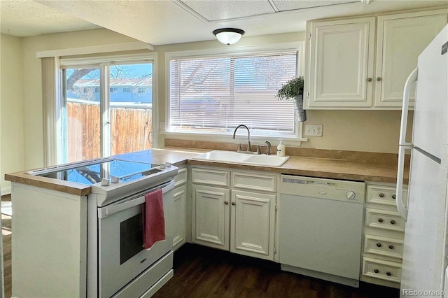 kitchen with sink, white appliances, white cabinetry, dark hardwood / wood-style floors, and kitchen peninsula