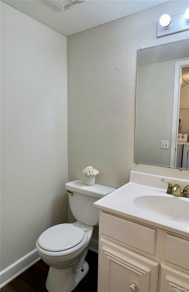 bathroom with vanity, washer and dryer, and toilet