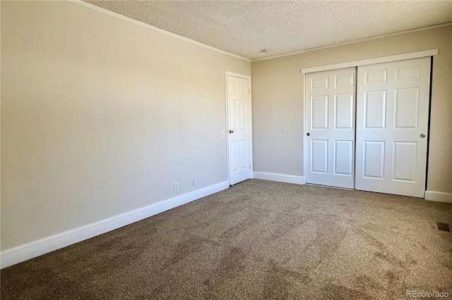 unfurnished bedroom featuring ornamental molding, carpet flooring, a textured ceiling, and a closet