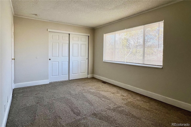 unfurnished bedroom with crown molding, carpet floors, a closet, and a textured ceiling