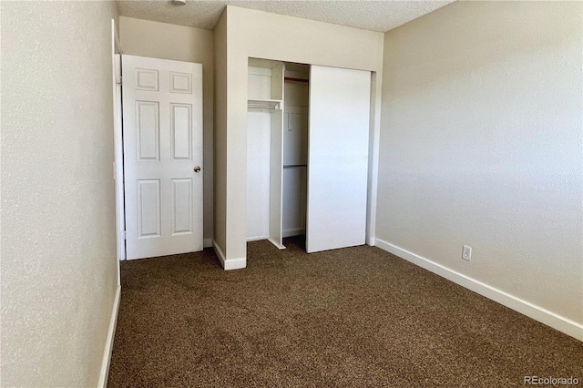 unfurnished bedroom with dark colored carpet, a textured ceiling, and a closet