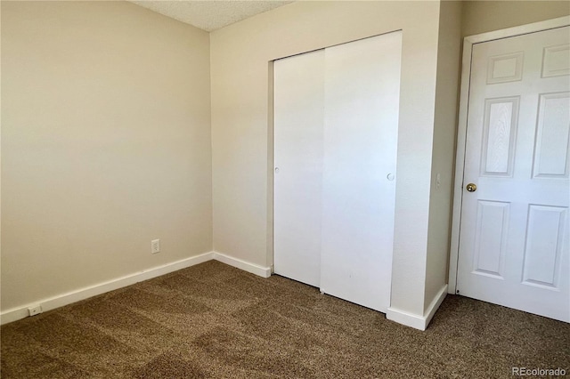 unfurnished bedroom featuring dark carpet and a closet