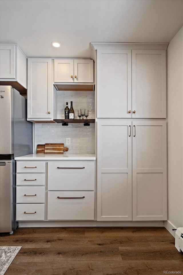 kitchen with stainless steel refrigerator, white cabinetry, dark wood-type flooring, and decorative backsplash