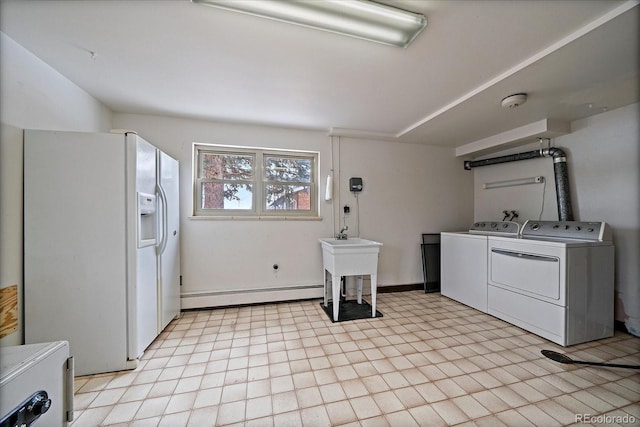 clothes washing area featuring independent washer and dryer, a baseboard radiator, and sink