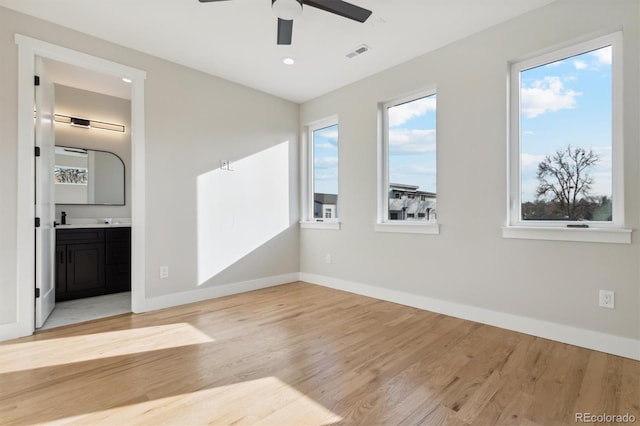 unfurnished bedroom featuring connected bathroom, ceiling fan, and light wood-type flooring