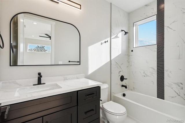 full bathroom with vanity, tiled shower / bath combo, toilet, and ceiling fan