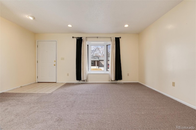 empty room with light colored carpet and a textured ceiling