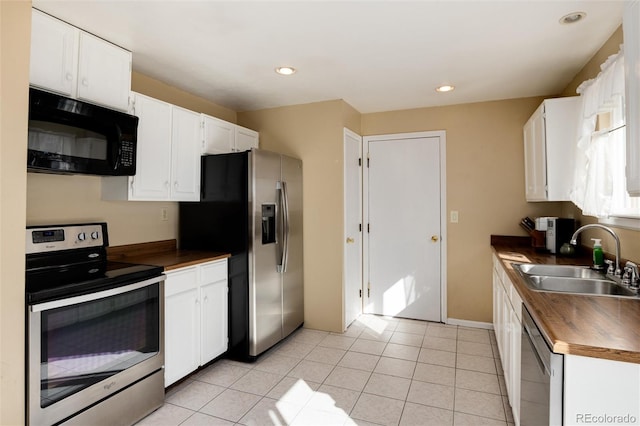 kitchen with appliances with stainless steel finishes, sink, light tile patterned floors, and white cabinets