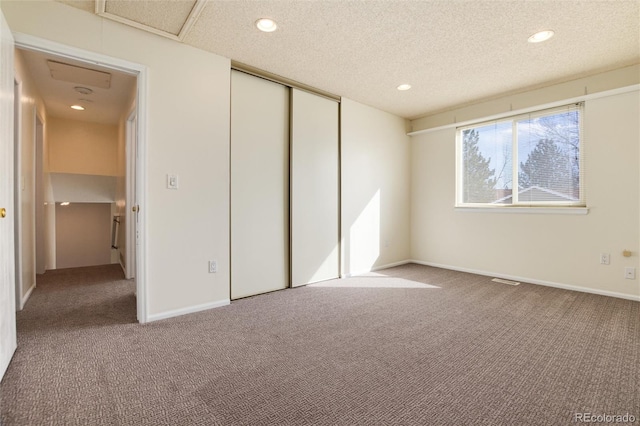 unfurnished bedroom with carpet floors, a textured ceiling, and a closet