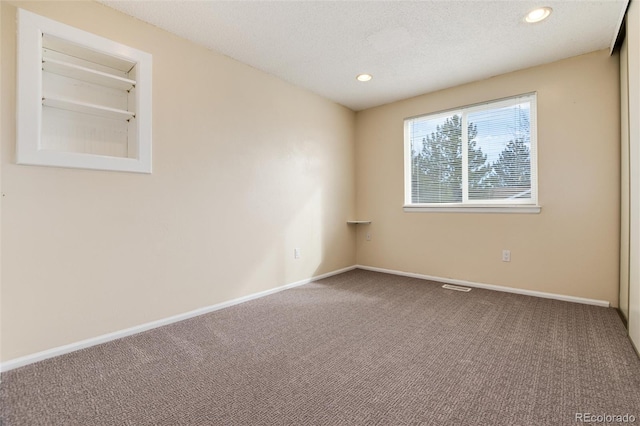 spare room with a textured ceiling and carpet flooring