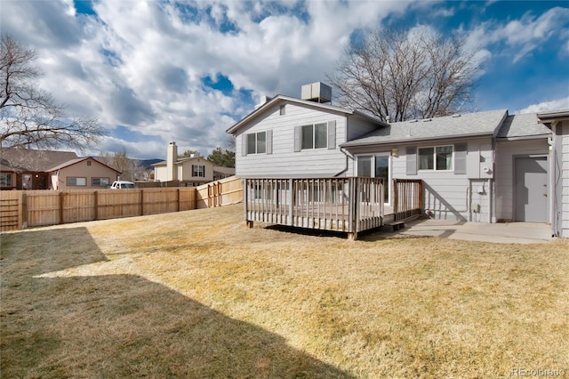 rear view of property with cooling unit, a deck, and a lawn